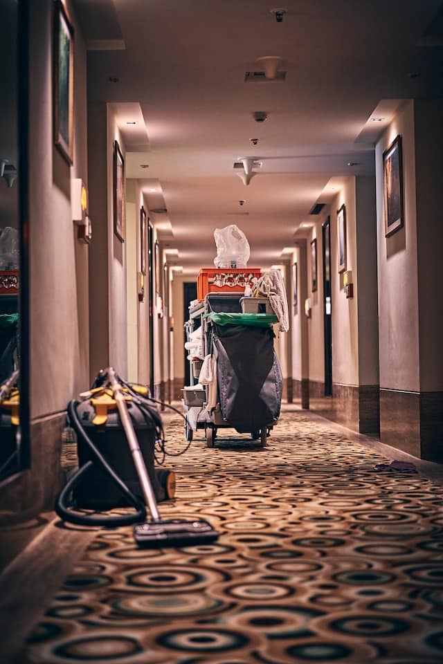 A photo of a person struggling to clean their house with a traditional vacuum cleaner